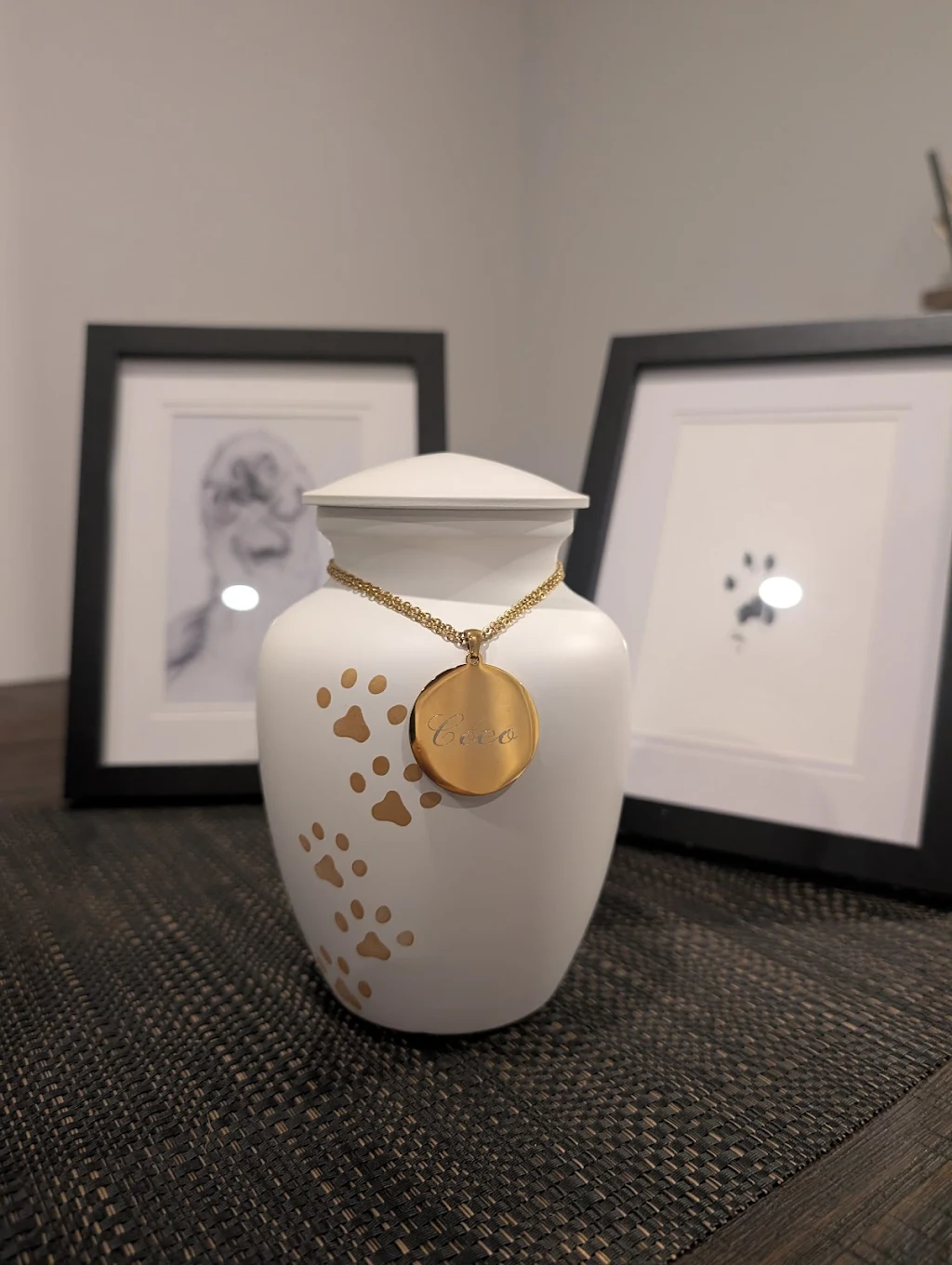 Coco's white urn with gold engraved pendant and framed paw print