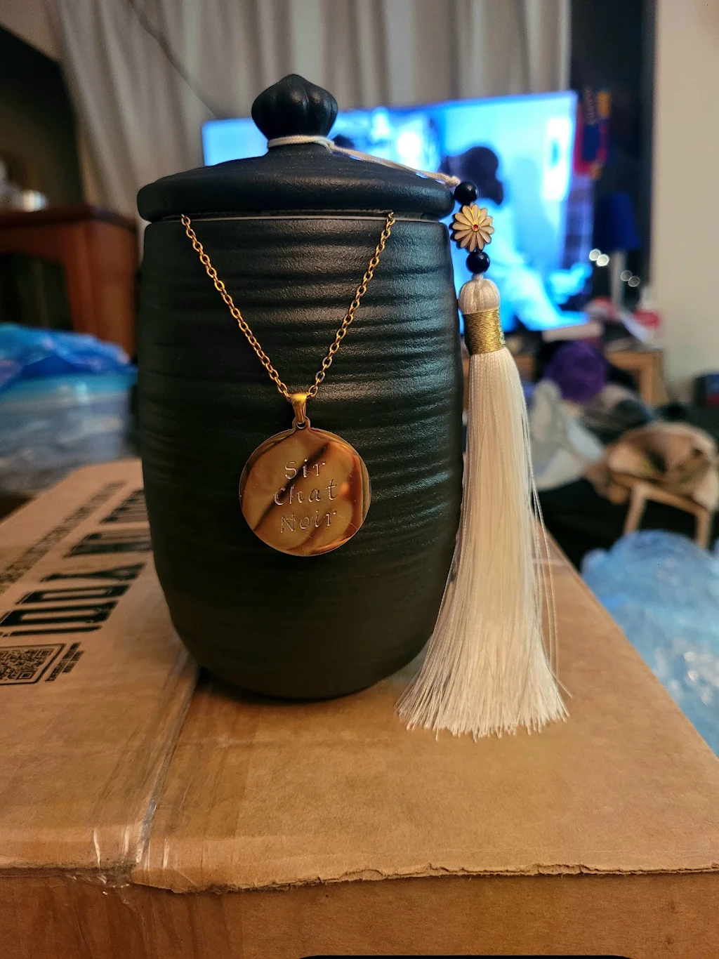 Sir Chat Noir's black urn with gold engraved pendant and white tassel